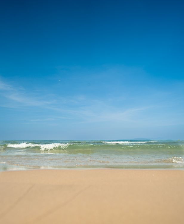 Tranquil sandy beach in Da Nang, Vietnam — clear blue skies and calm waves, perfect for combining dental treatment with a beach holiday.