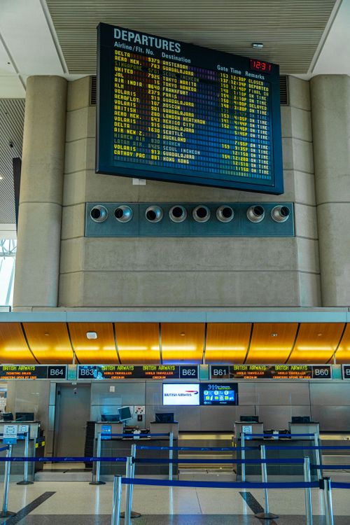 Digital departure board and airline check-in counters at a modern airport terminal
