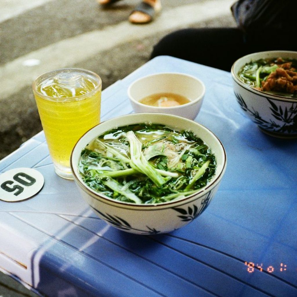 Noodle bowl served on a plastic stool in a street-food setting