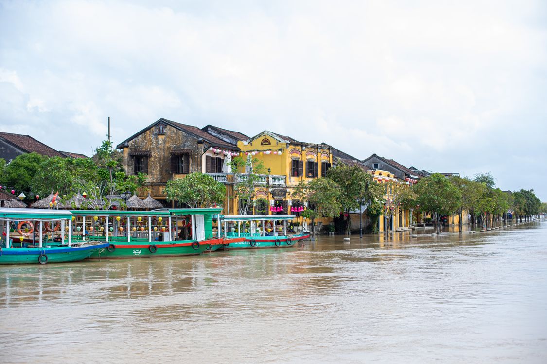 Traditional boats on the Thu Bon River reflecting Hoi An historic yellow buildings