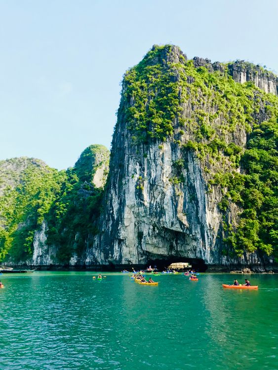 Kayakers paddling through the calm waters of Lan Ha Bay surrounded by towering limestone cliffs