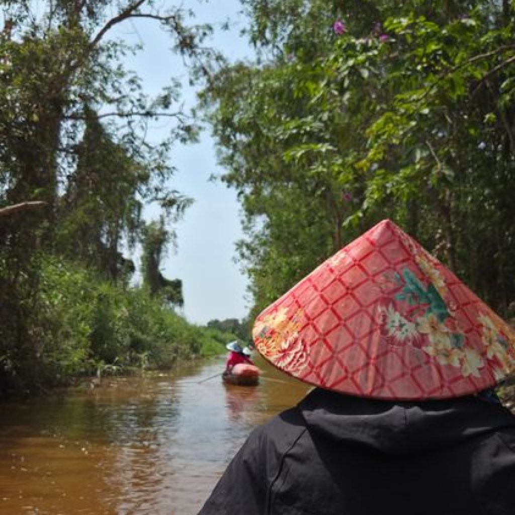 Small boat traveling through a narrow tropical canal