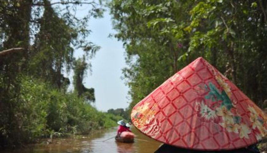Sampan boat ride through the narrow palm-lined canals of the Mekong Delta in Ben Tre, Vietnam