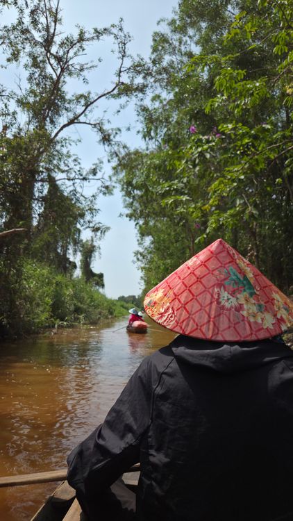 Sampan boat ride through the narrow palm-lined canals of the Mekong Delta in Ben Tre, Vietnam