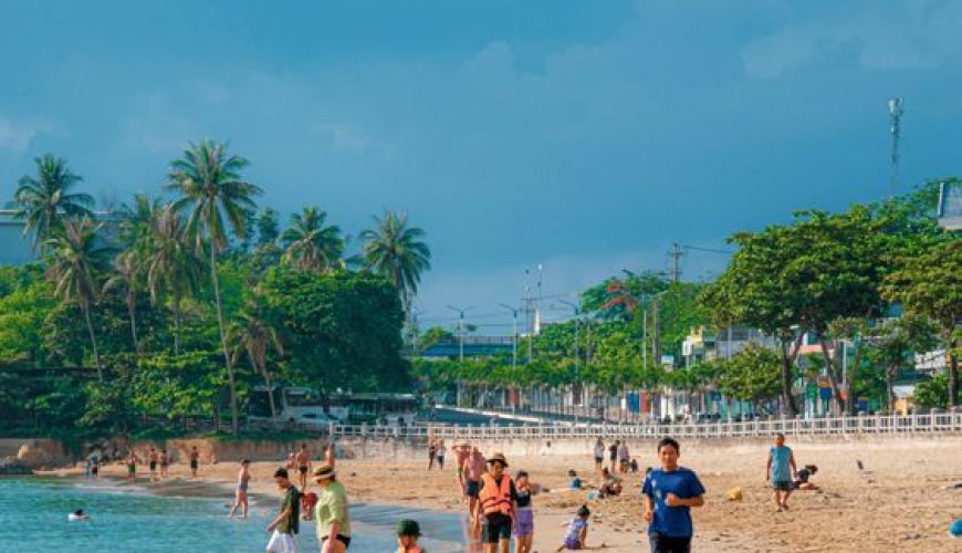 Sunny day at Nha Trang beach with clear blue water and people enjoying the coast