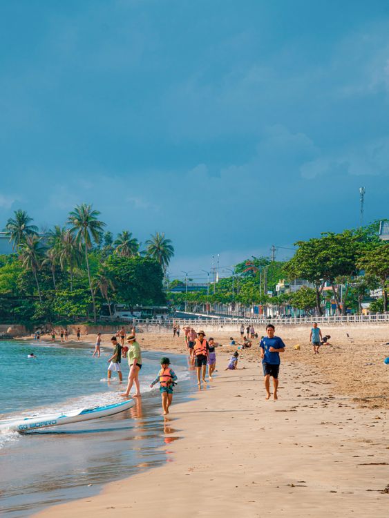Sunny day at Nha Trang beach with clear blue water and people enjoying the coast