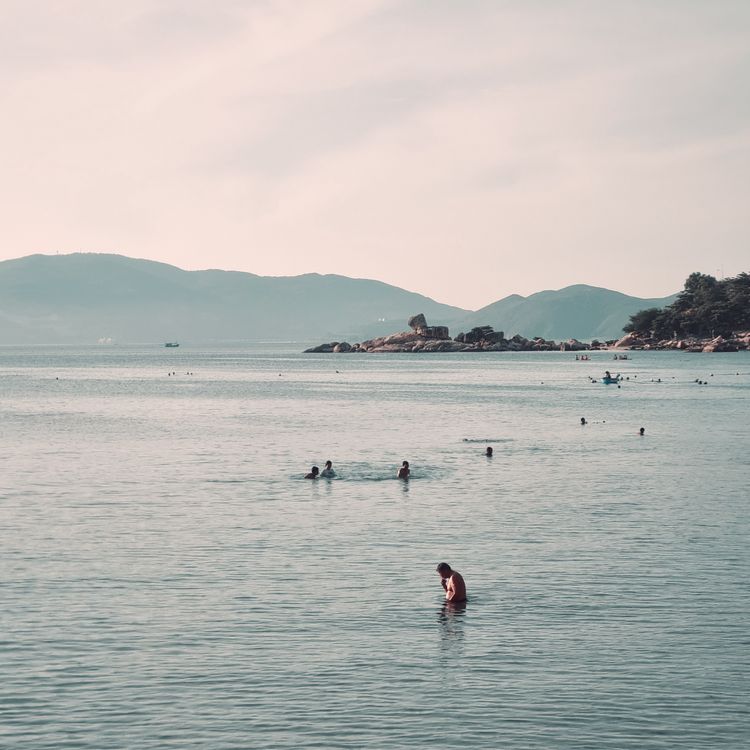 Relaxing beach scene in Nha Trang with people swimming and distant islands visible