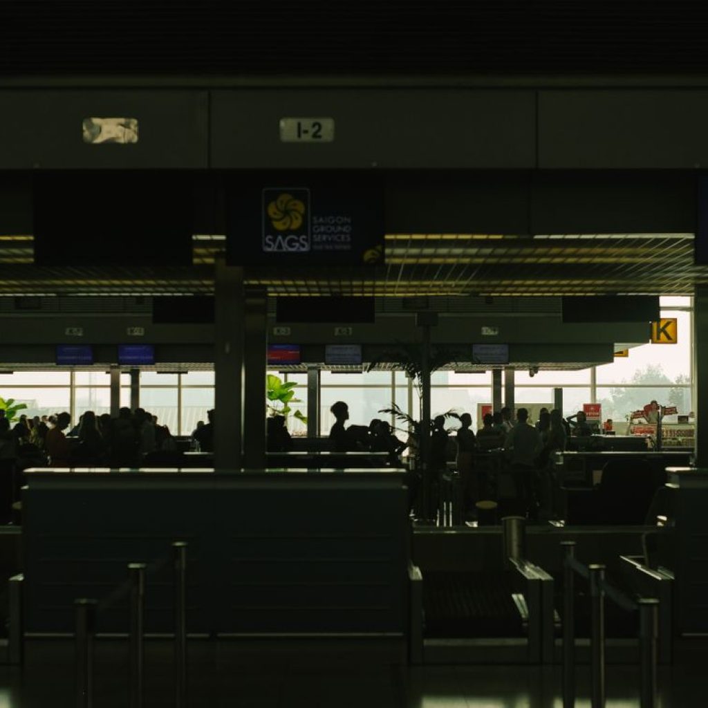Airport check-in hall with travelers and Saigon Ground Services signs
