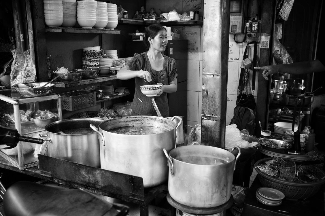Traditional Vietnamese street food vendor preparing dishes at a market stall in Ho Chi Minh City