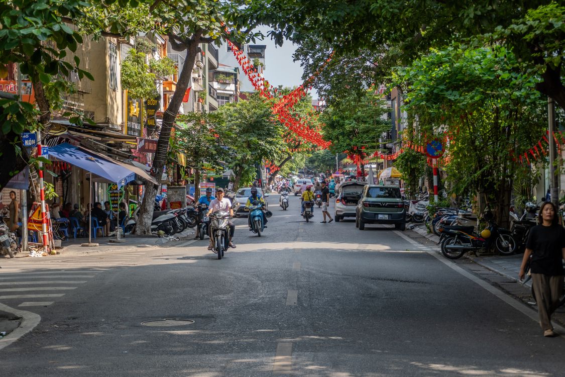 Bustling Hanoi street scene with Vietnamese flags — summer in the north is hot, humid, and full of character.