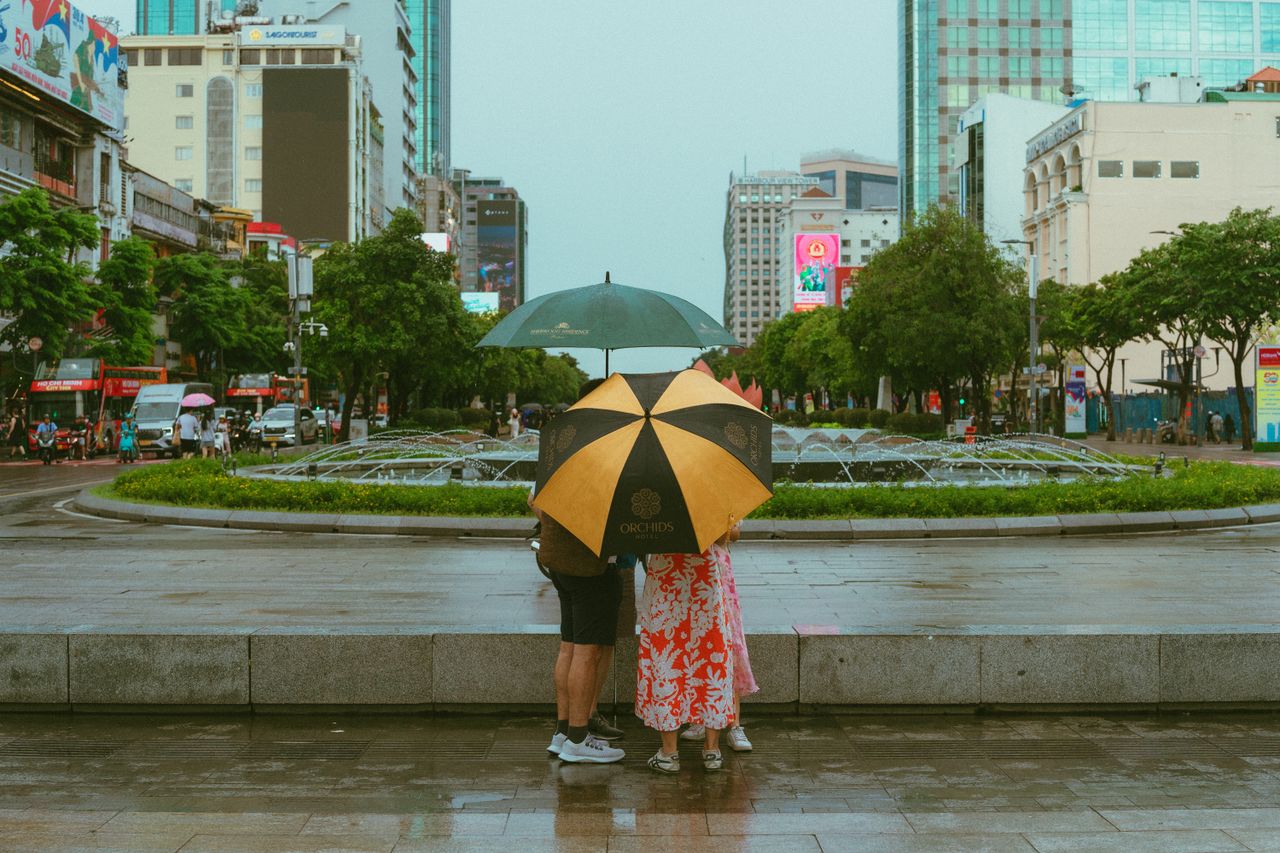 People walking with umbrellas in rainy Ho Chi Minh City street