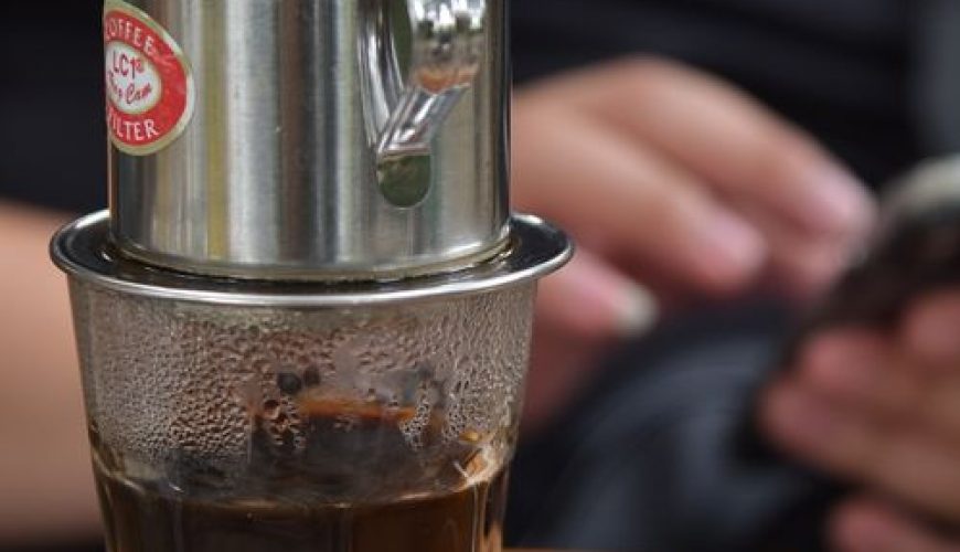 Vietnamese coffee dripping through a traditional phin filter over a glass of condensed milk