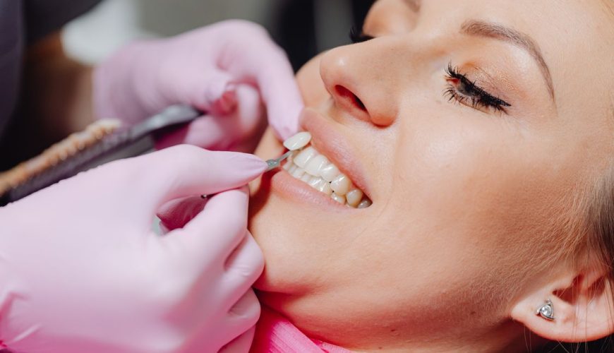 Dentist applying a porcelain veneer to a patient’s teeth in a modern dental clinic