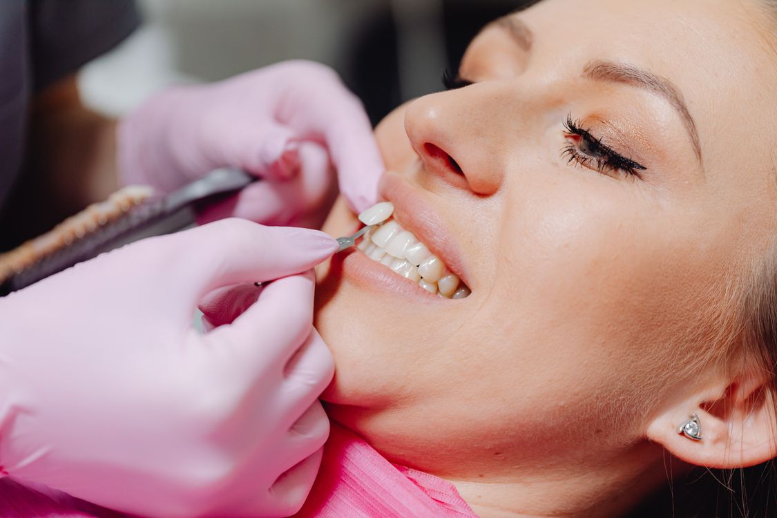 Dentist applying a porcelain veneer to a patient’s teeth in a modern dental clinic