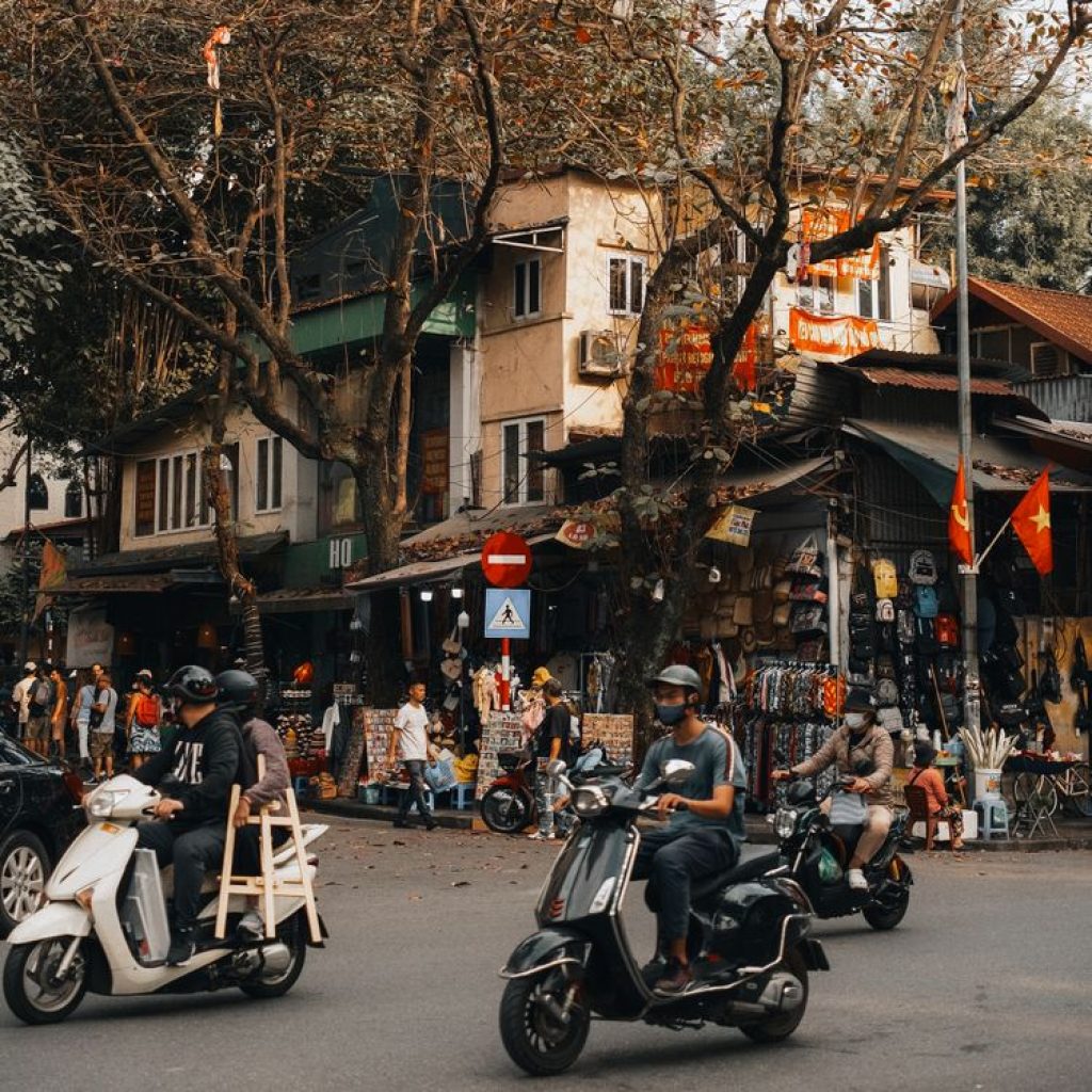 Busy street scene in Hanoi Old Quarter with scooters, shops and local life