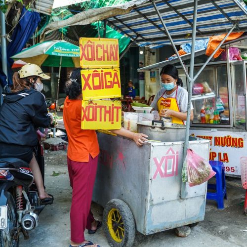 Vietnamese street food vendor selling traditional dishes at a bustling market in Vietnam