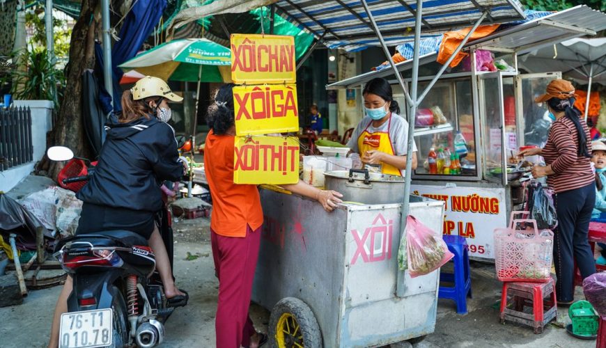 Vietnamese street food vendor selling traditional dishes at a bustling market in Vietnam
