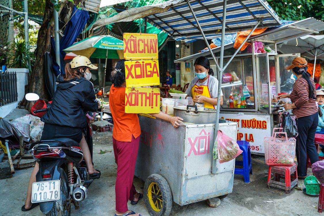 Vietnamese street food vendor selling traditional dishes at a bustling market in Vietnam
