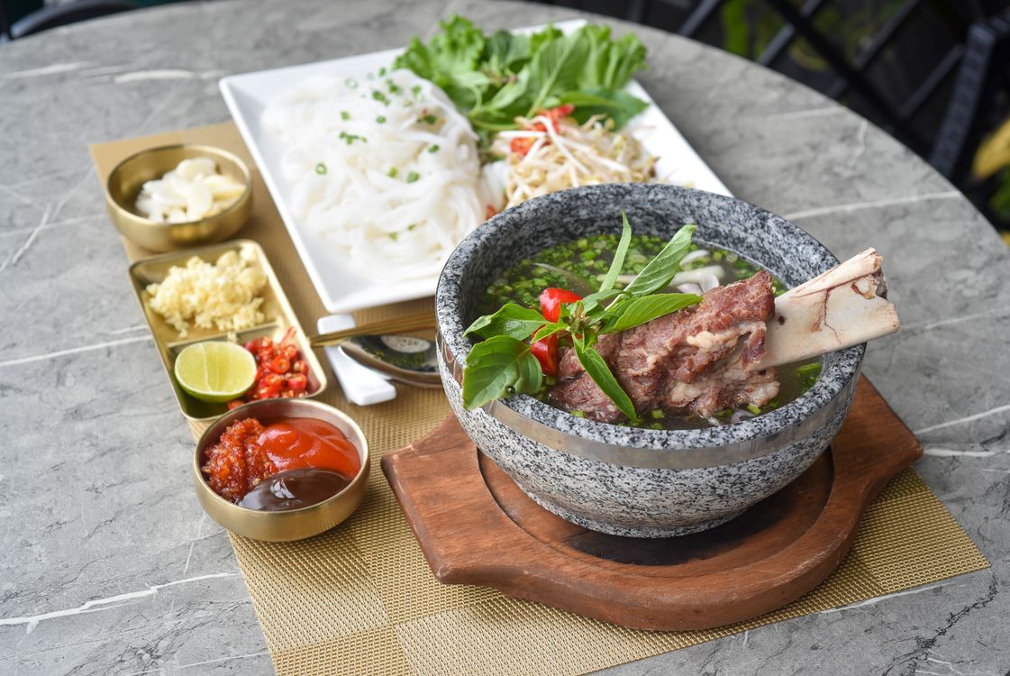 Bowl of Vietnamese fish cake noodle soup (bun ca) with fresh herbs