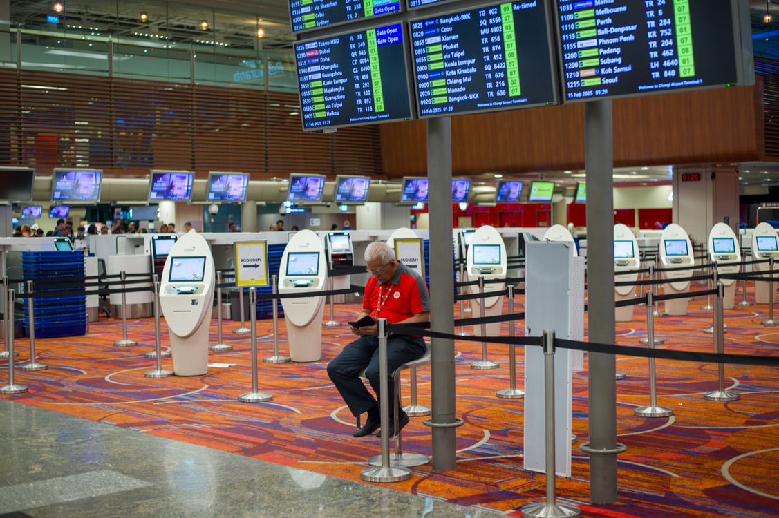 Airport check-in area with flight information screens and kiosks