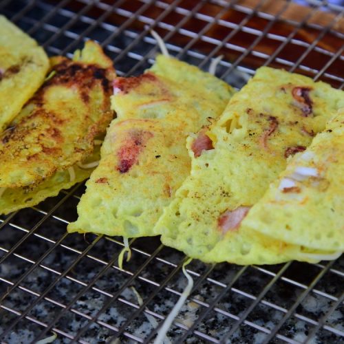 Crispy Vietnamese banh xeo pancake sizzling on a grill with fresh shrimp and pork, Can Tho specialty