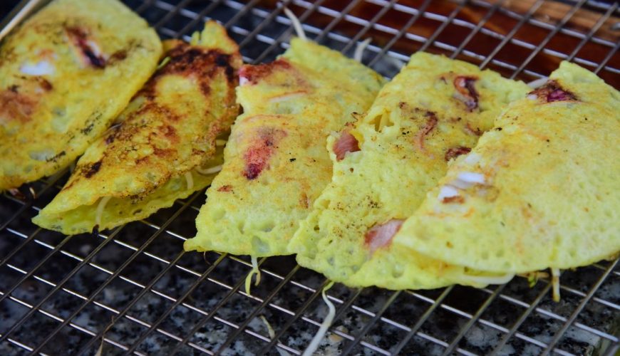 Crispy Vietnamese banh xeo pancake sizzling on a grill with fresh shrimp and pork, Can Tho specialty