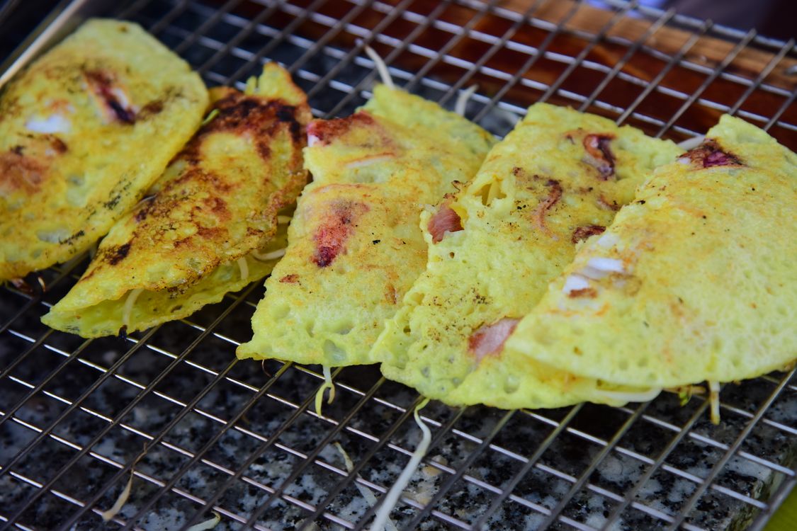 Crispy Vietnamese banh xeo pancake sizzling on a grill with fresh shrimp and pork, Can Tho specialty