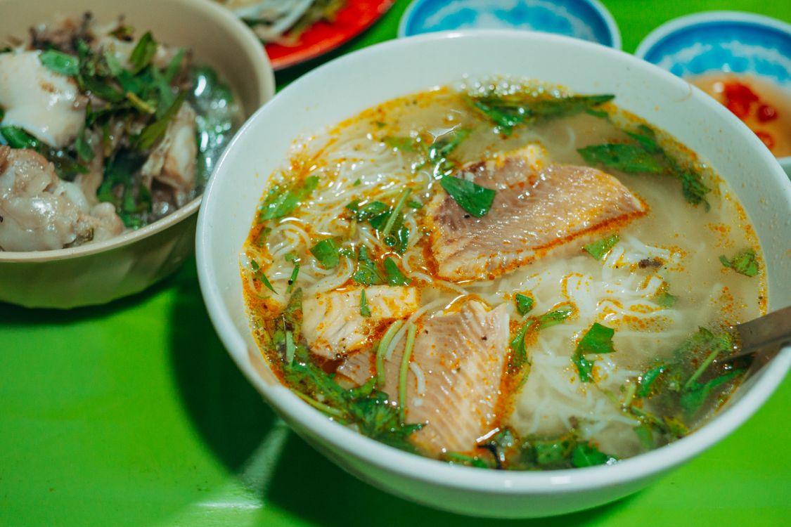Bowl of Vietnamese fish noodle soup bun ca with fresh herbs, Can Tho style