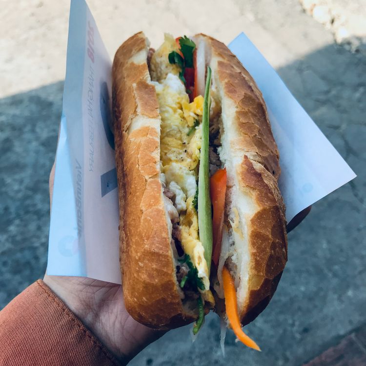 Fresh Vietnamese banh mi sandwich held outdoors