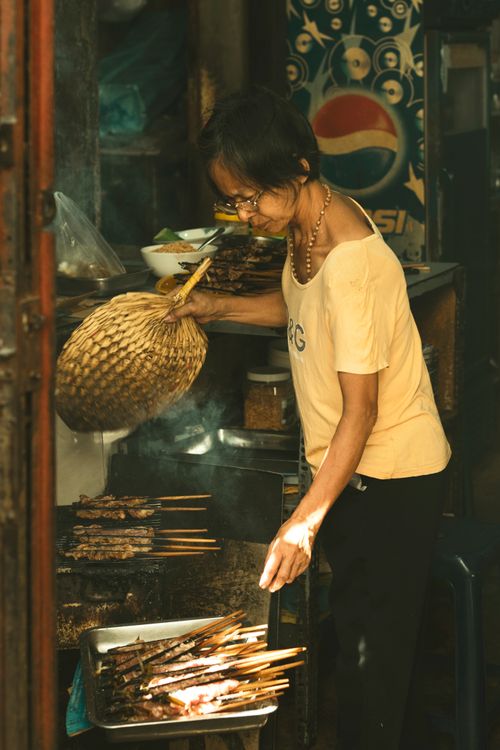 Street vendor grilling meat skewers in Vietnam