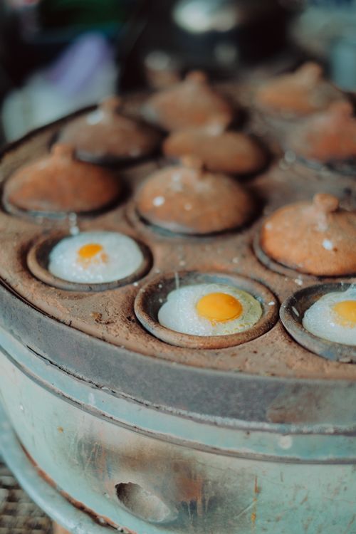 Quail eggs cooking in a traditional Vietnamese street food pan