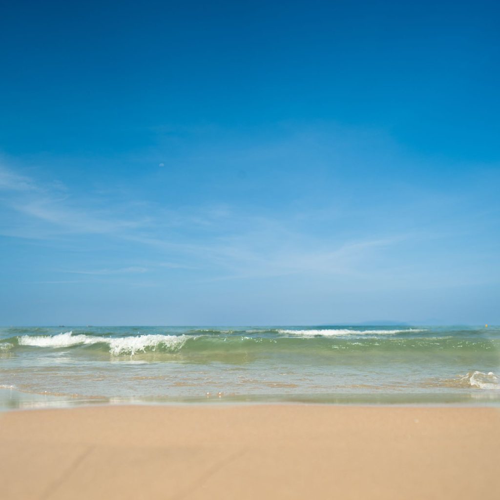 Wide sandy beach with gentle waves beneath a clear sky