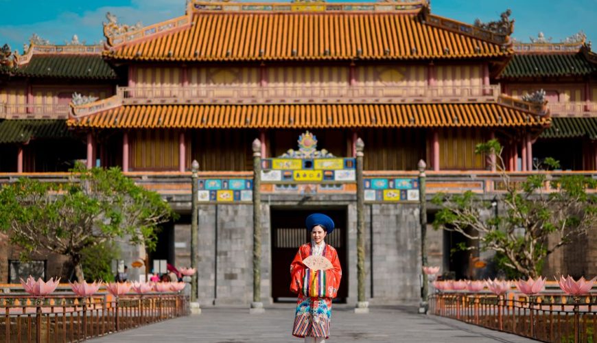 Woman in traditional ao dai visiting the Imperial City in Hue, Vietnam
