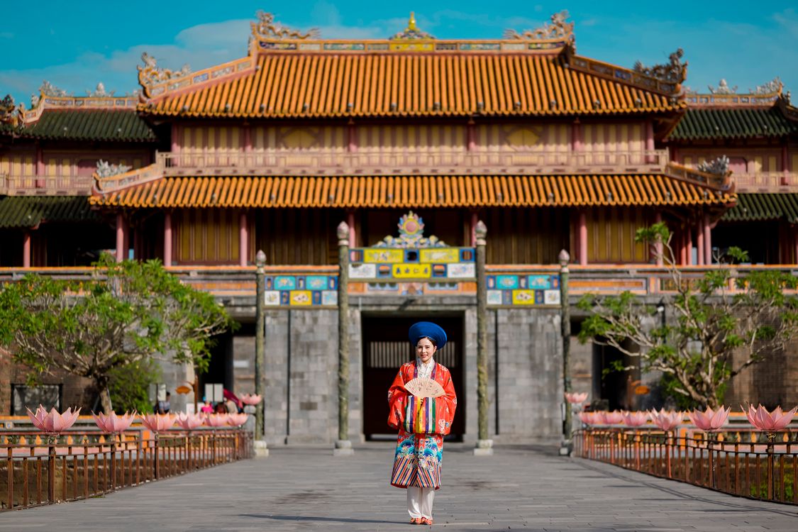 Woman in traditional ao dai visiting the Imperial City in Hue, Vietnam