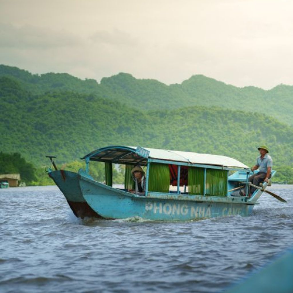 Traditional wooden dragon boat carrying tourists on the Son River near Phong Nha Cave, Quang Binh
