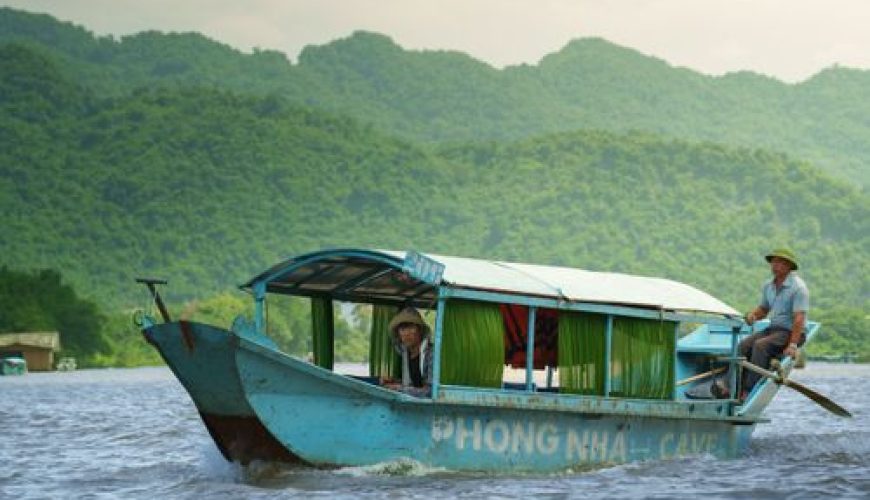 Traditional wooden dragon boat carrying tourists on the Son River near Phong Nha Cave, Quang Binh