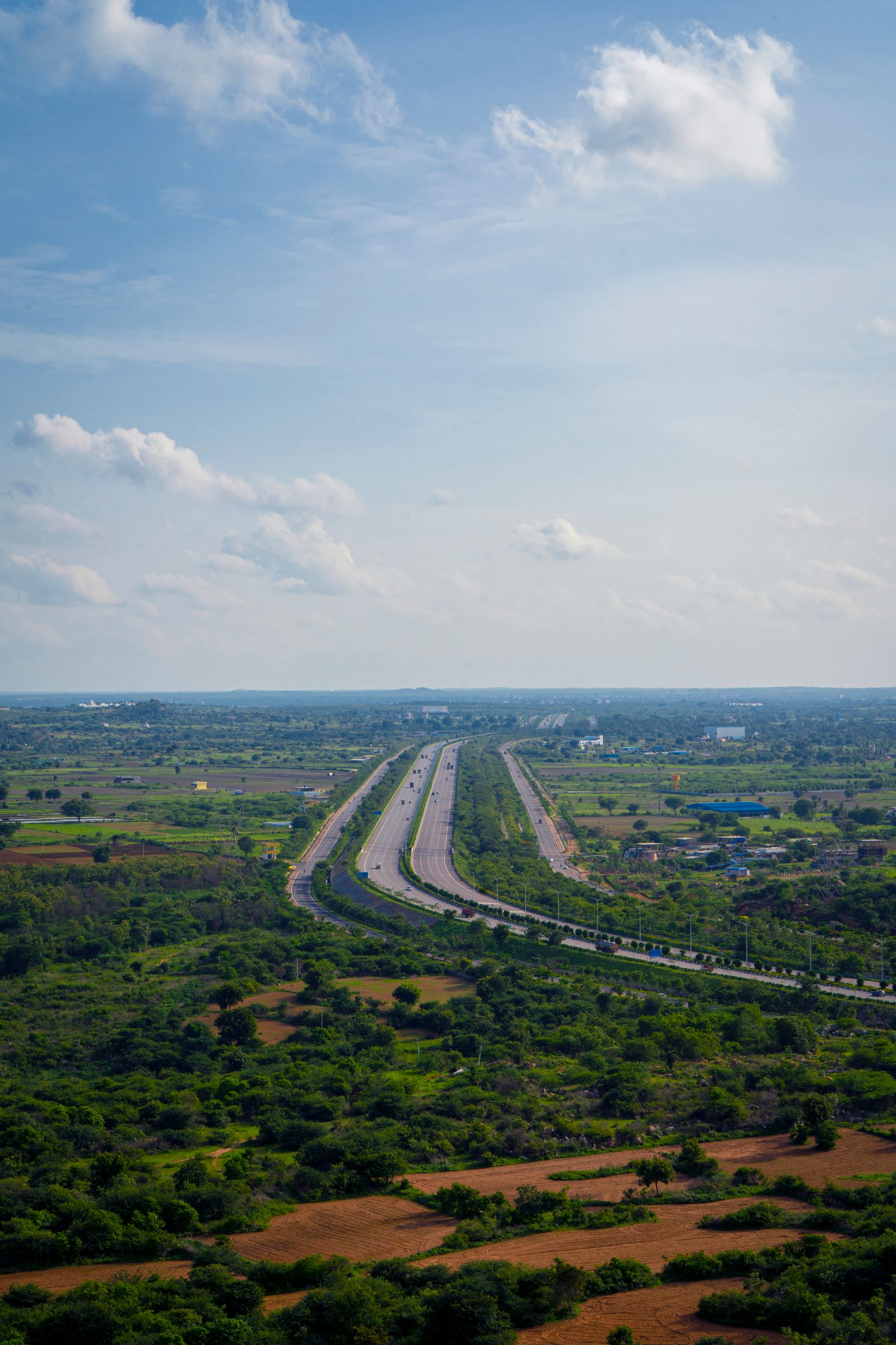 Aerial view of a divided expressway crossing green countryside near Hyderabad