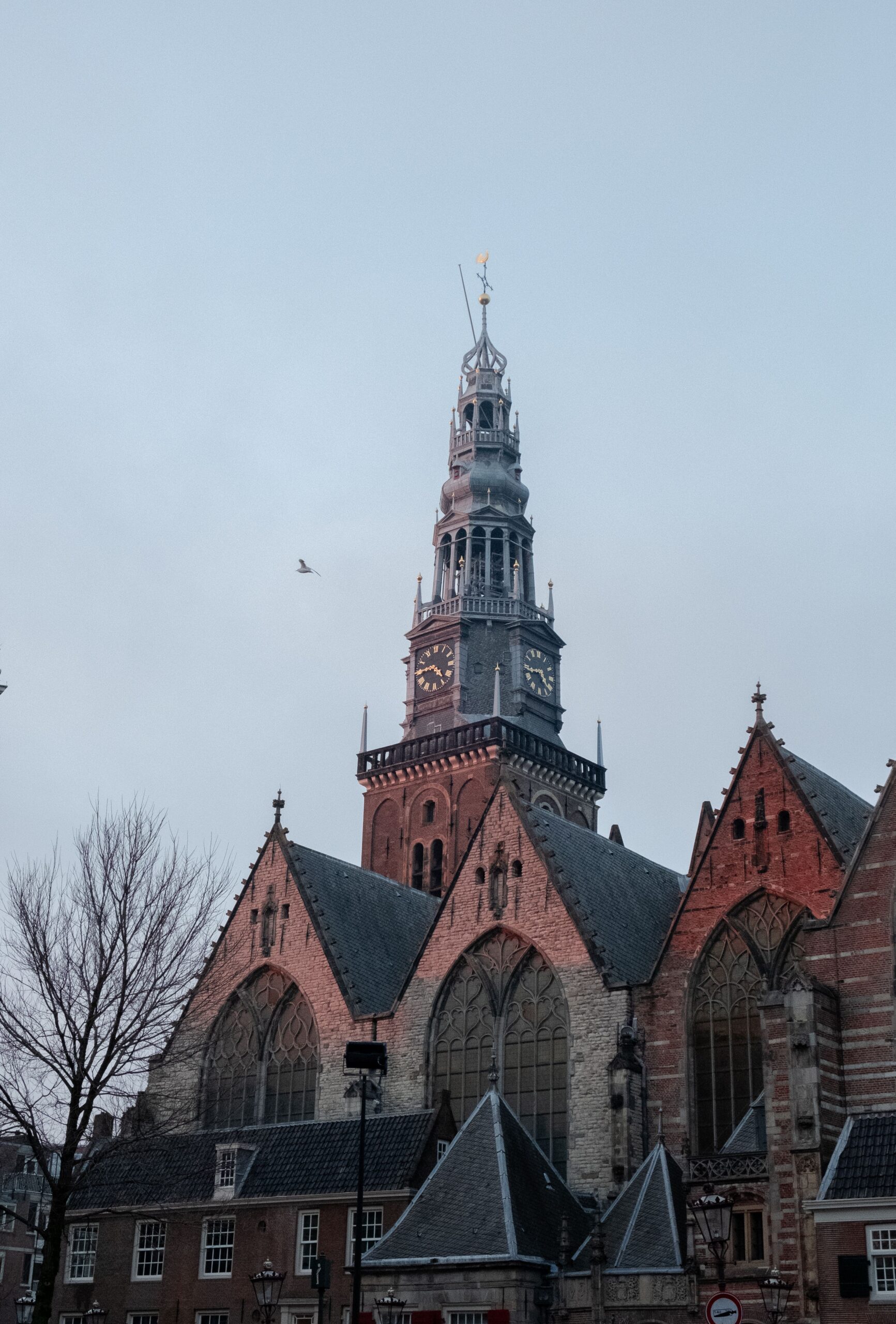 The brick nave and clock tower of Amsterdam’s Oude Kerk rise above nearby rooftops.
