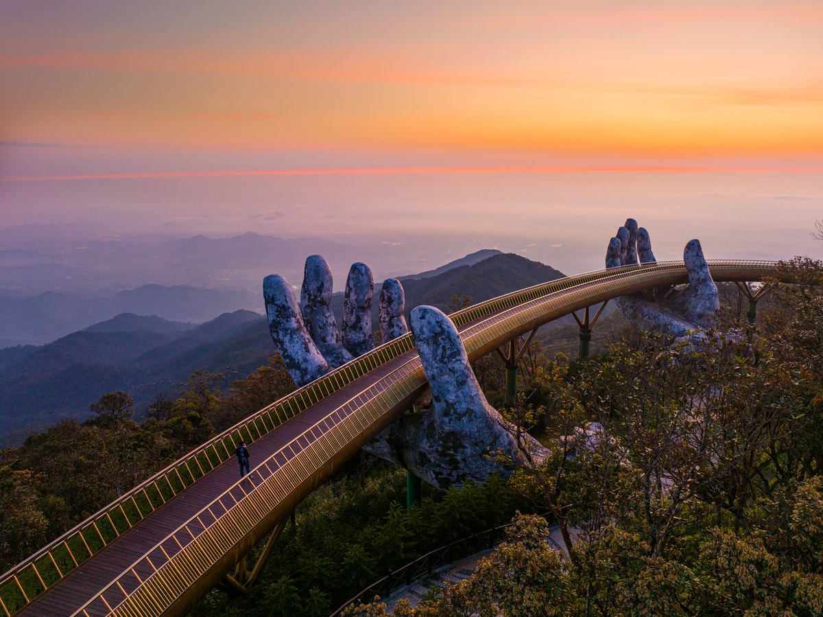 Aerial view of the curved Golden Bridge supported by two giant stone hands at Ba Na Hills, Vietnam