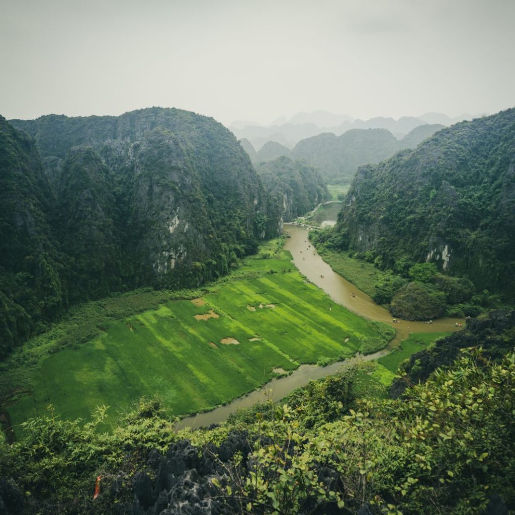 Aerial panorama of the Tam Coc river valley in Ninh Binh with a winding river, green rice paddies and towering limestone karst mountains