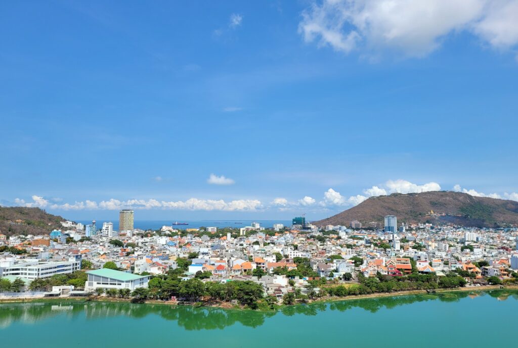 Aerial view of a coastal Vietnamese city with the sea, wooded hills and dense city blocks along the waterfront