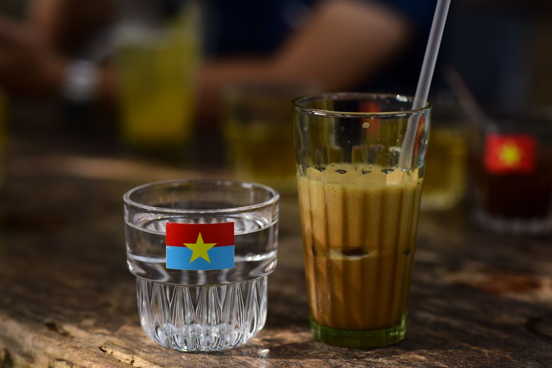 Foamy Vietnamese-style coffee beside a glass of water.