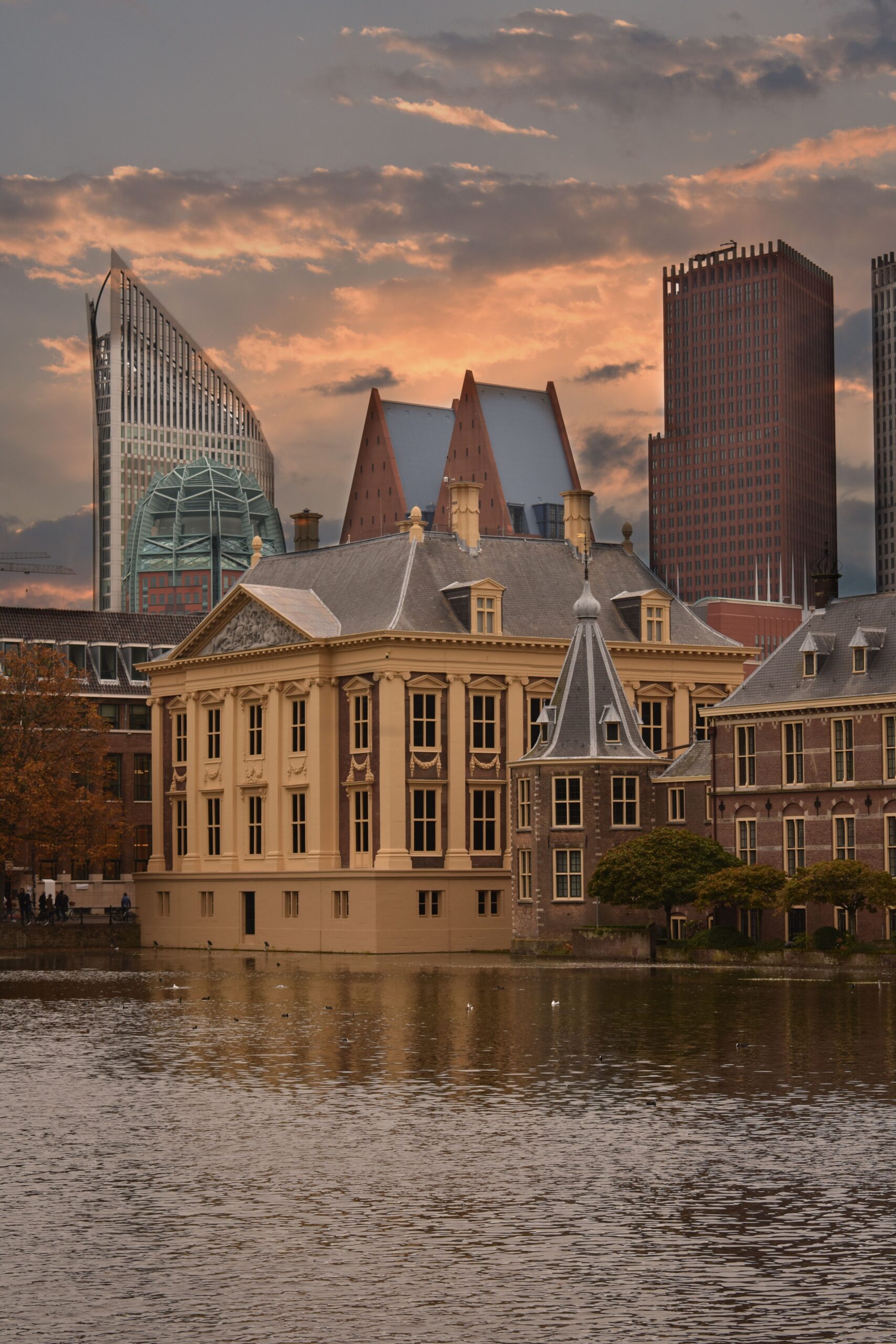 Historic waterfront buildings and The Hague skyline at sunset.