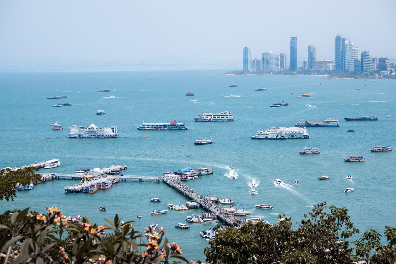 Boats, a ferry pier and the skyline across Pattaya Bay