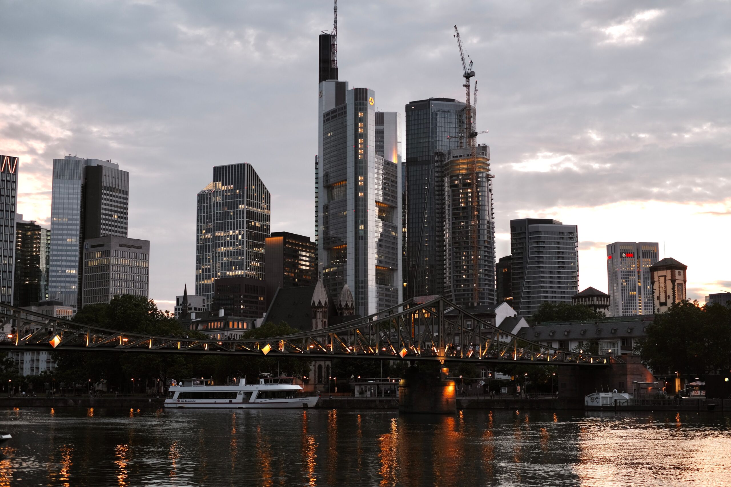 Frankfurt skyscrapers, a river bridge and reflections at dusk.