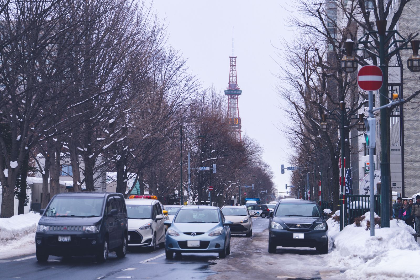 Cars on a snow-lined Sapporo street with the TV Tower in the distance