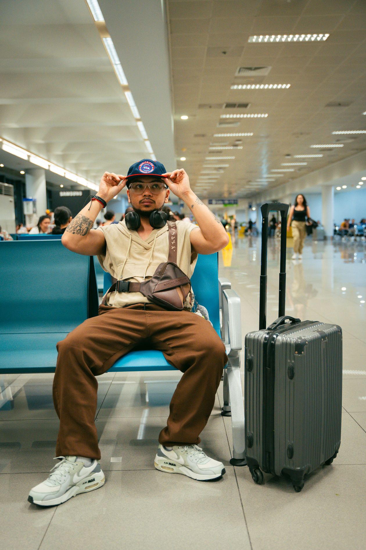 Traveler sitting in an airport terminal beside a wheeled suitcase