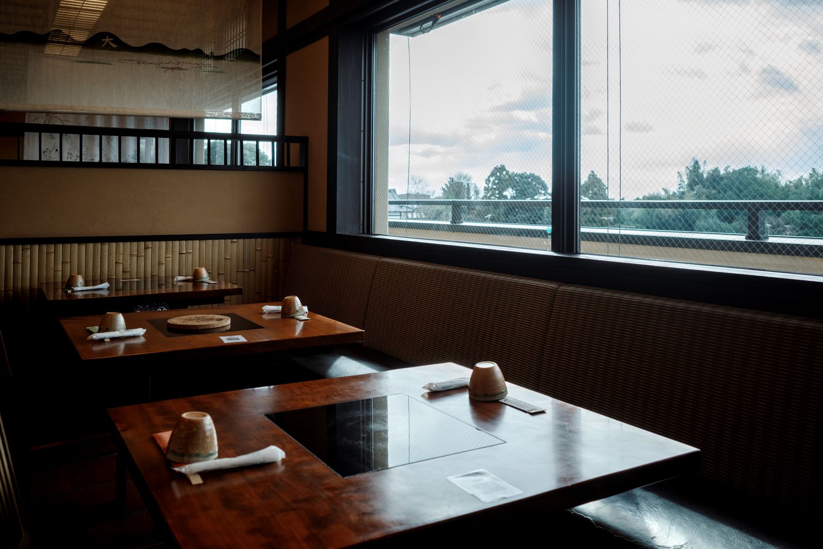 Tables and cushioned seating beside a window in a Kyoto restaurant