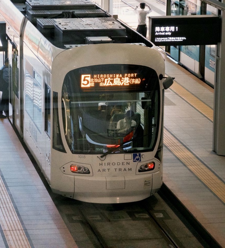 Front of a green-and-white tram at a Hiroshima station platform