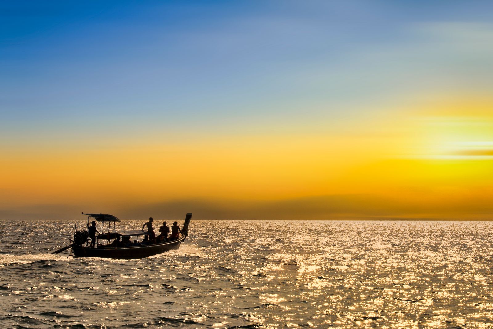 Long-tail boat silhouetted against a golden sunset off Koh Samui